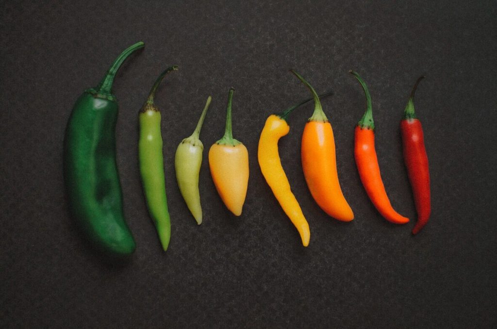 Several varieties of chili peppers spread on a black background.